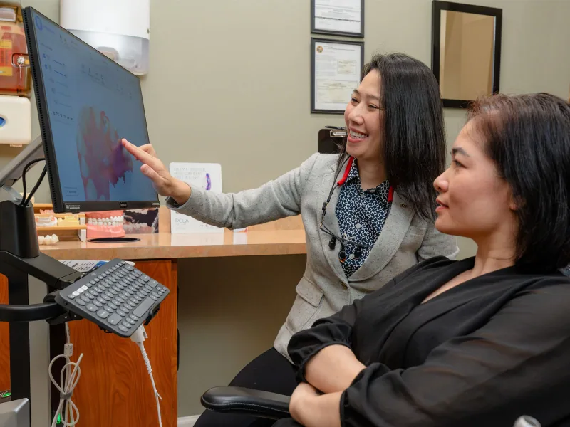 Dr. Hien Nguyen explaining a dental care plan to a patient seated beside her.